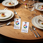 Two white Google review cards with the Google G logo and the text 'Review us on Google' are arranged on a wooden surface with white and yellow flowers around them.